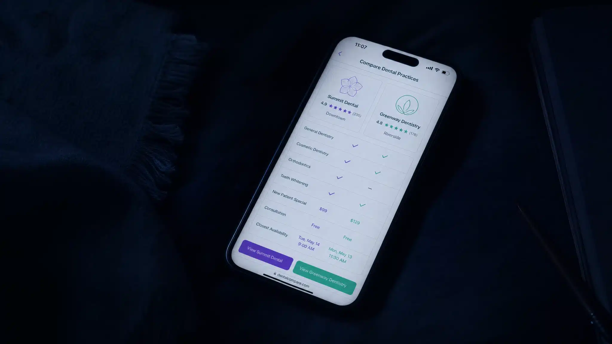 A phone glowing at night comparing two dental practices by rating, price and availability.
